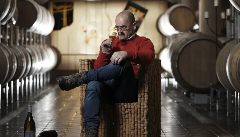 Uomo assapora vino Franz Haas in cantina tra botti.
