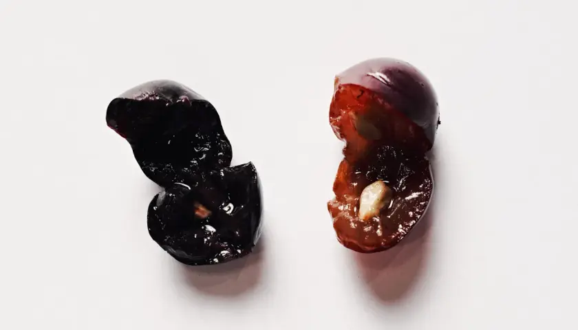 Due acini d'uva tagliati a metà, uno scuro e uno più chiaro, evocano la macerazione carbonica del vino.