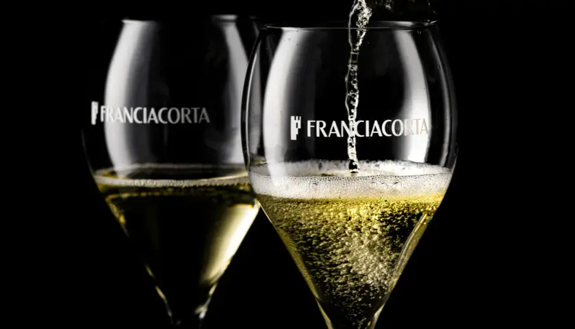Due calici di Franciacorta Saten, uno viene riempito, perfetti per ogni abbinamento.