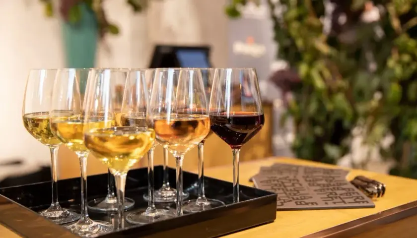 Calici di vino bianco, rosato e rosso su un vassoio nero. Un'esperienza di degustazione che non è barricata, ma aperta a tutti i sapori.