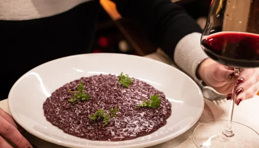 Risotto viola con prezzemolo, accompagnato da un calice di vino rosso. Perfetto per scoprire i migliori amarone abbinamenti.