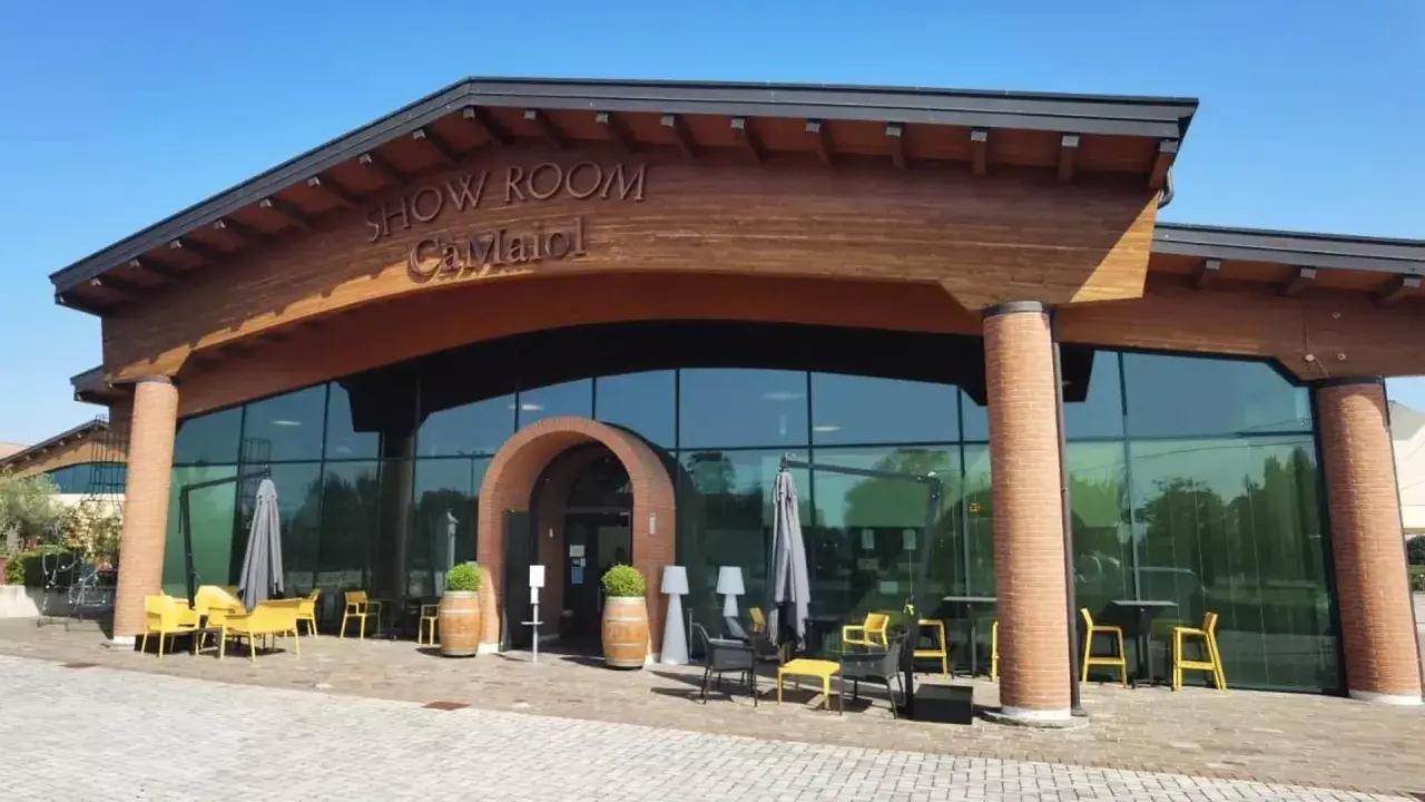 Show Room Ca' Maiol, un'elegante cantina con ampie vetrate e arredi esterni invitanti.