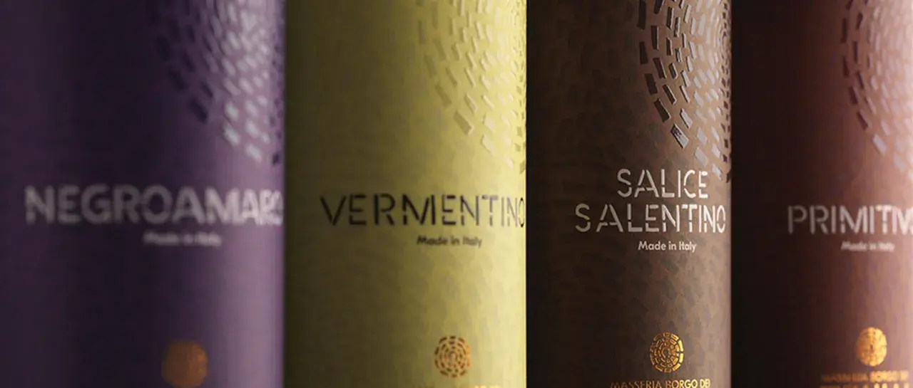 Etichetta vino esempio: bottiglie di Negroamaro, Vermentino, Salice Salentino e Primitivo, con dettagli dorati e texture uniche.