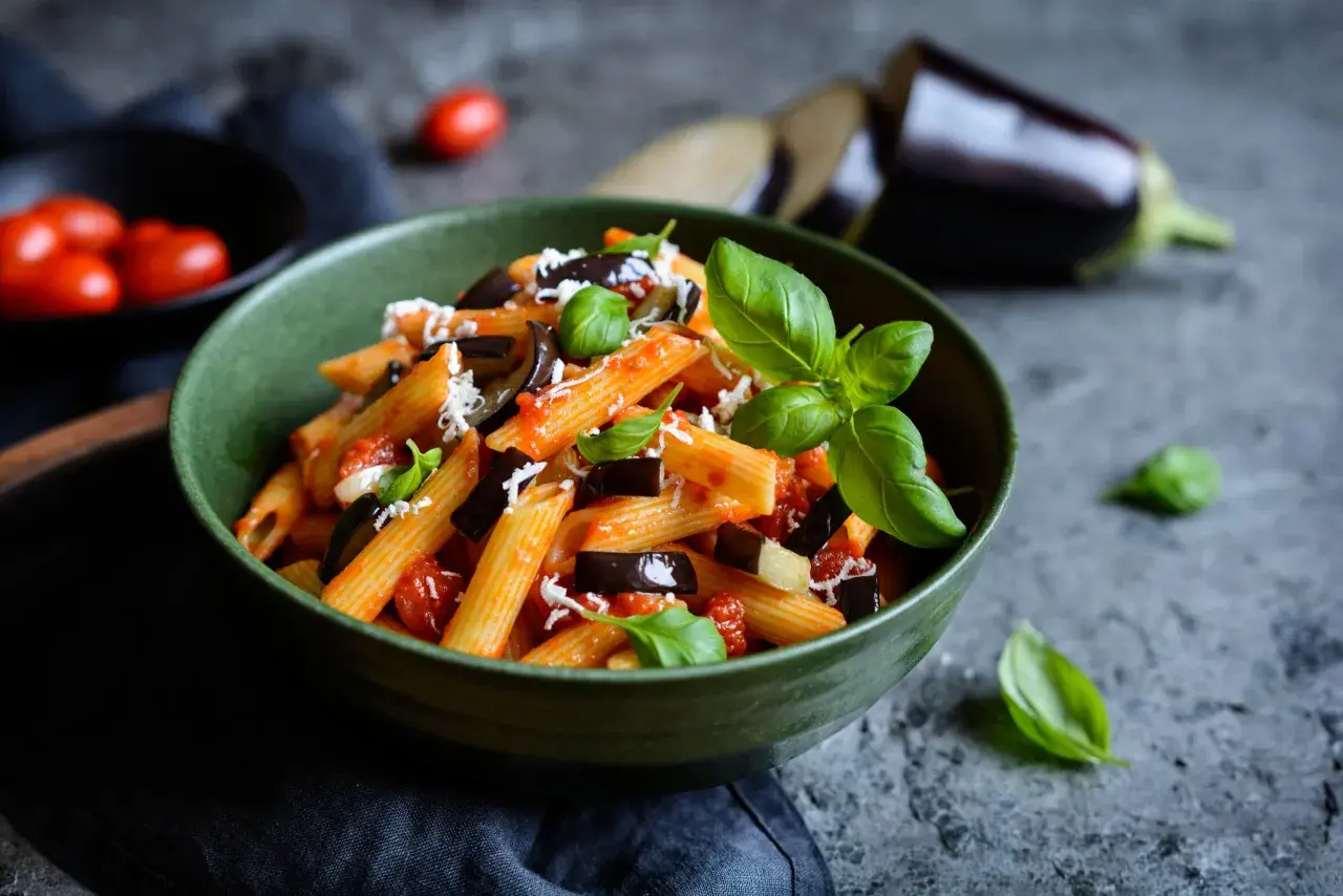 Piatto di pasta alla norma con melanzane, pomodoro e basilico, perfetto per un abbinamento vino.