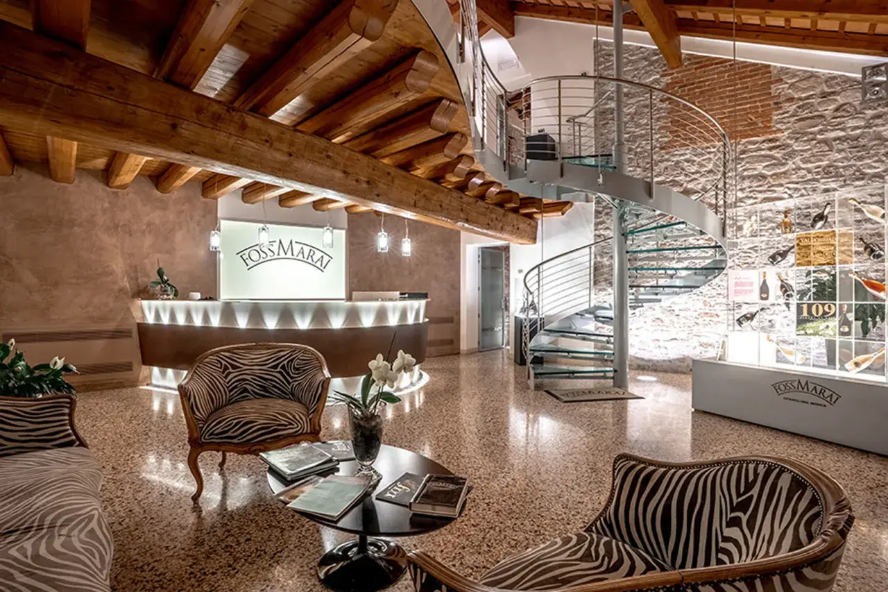 Interno di una cantina con reception, scala a chiocciola e esposizione di bottiglie. Ideale per cantine da visitare Valdobbiadene.