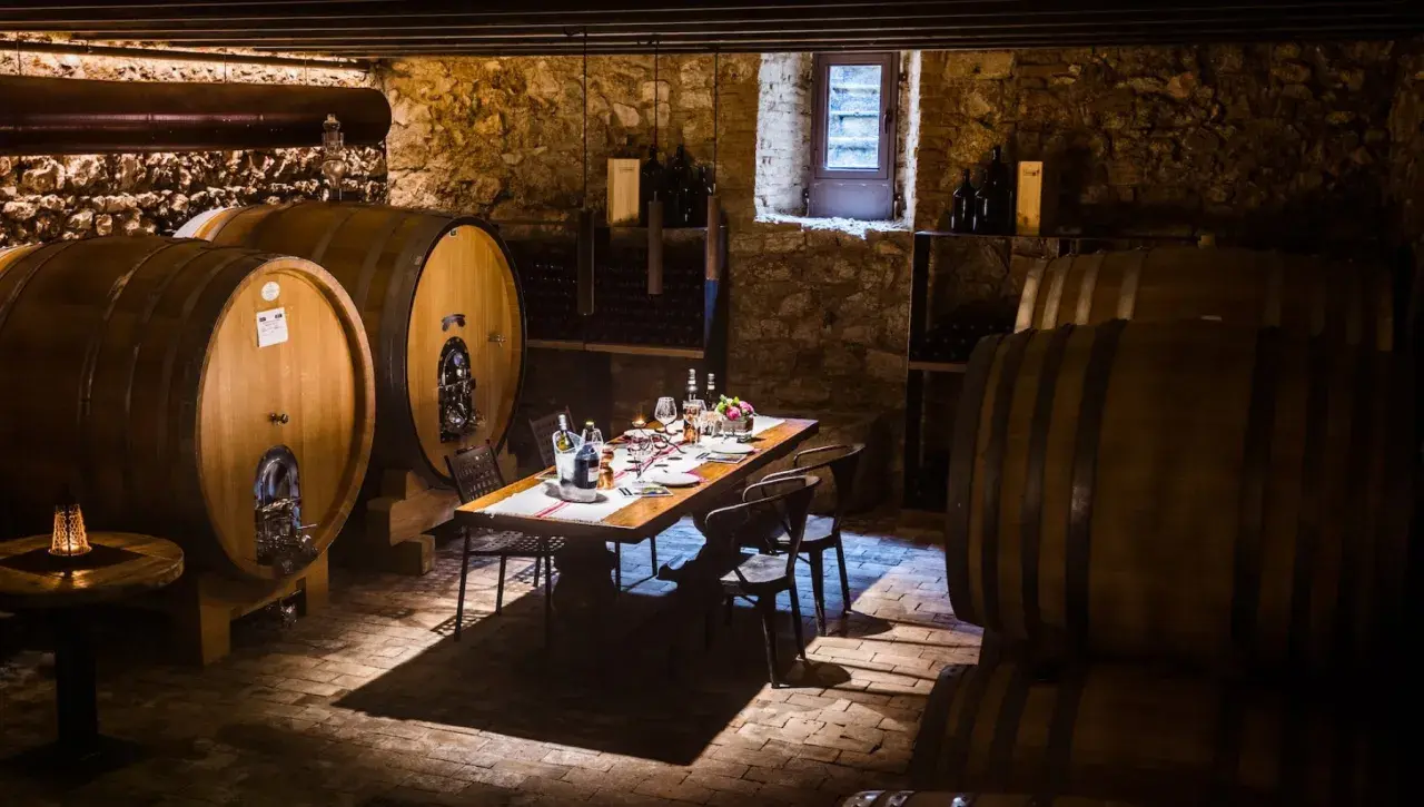 Cantine Valpolicella da visitare: un tavolo apparecchiato tra botti di legno e pietra, pronto per una degustazione.