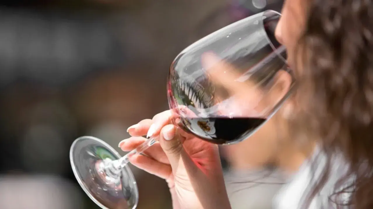 Donna assapora un vino amabile, con un sorso che promette piacere.