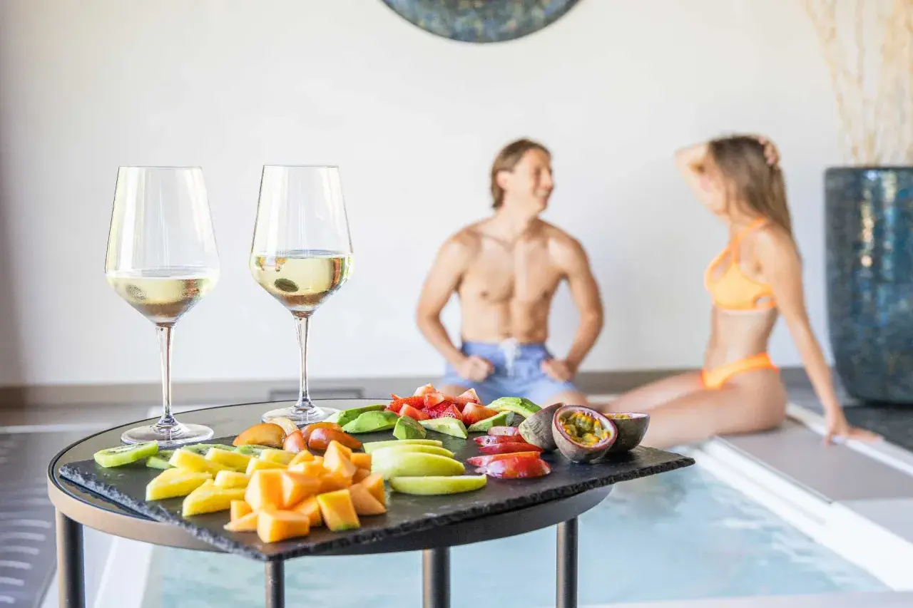 Coppia rilassata alle terme con degustazione di vino e frutta fresca. Un momento di puro piacere.