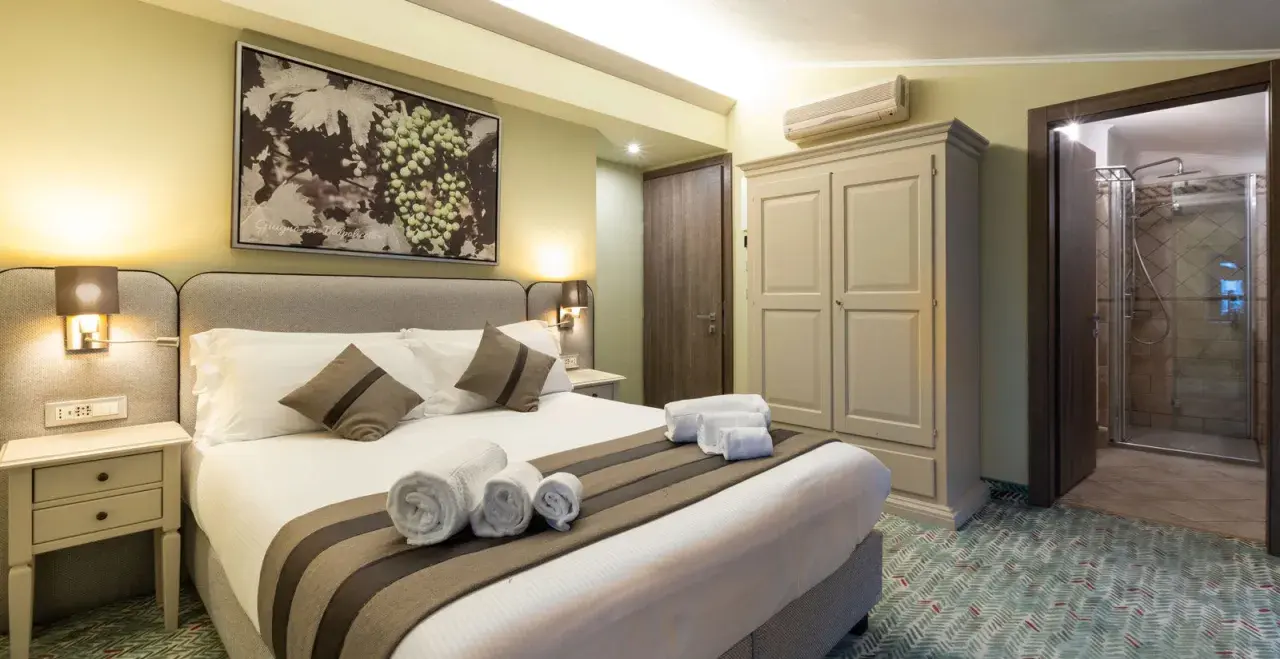 Camera accogliente con letto comodo, quadro di uva e un invito a dormire in cantina a Valpolicella.