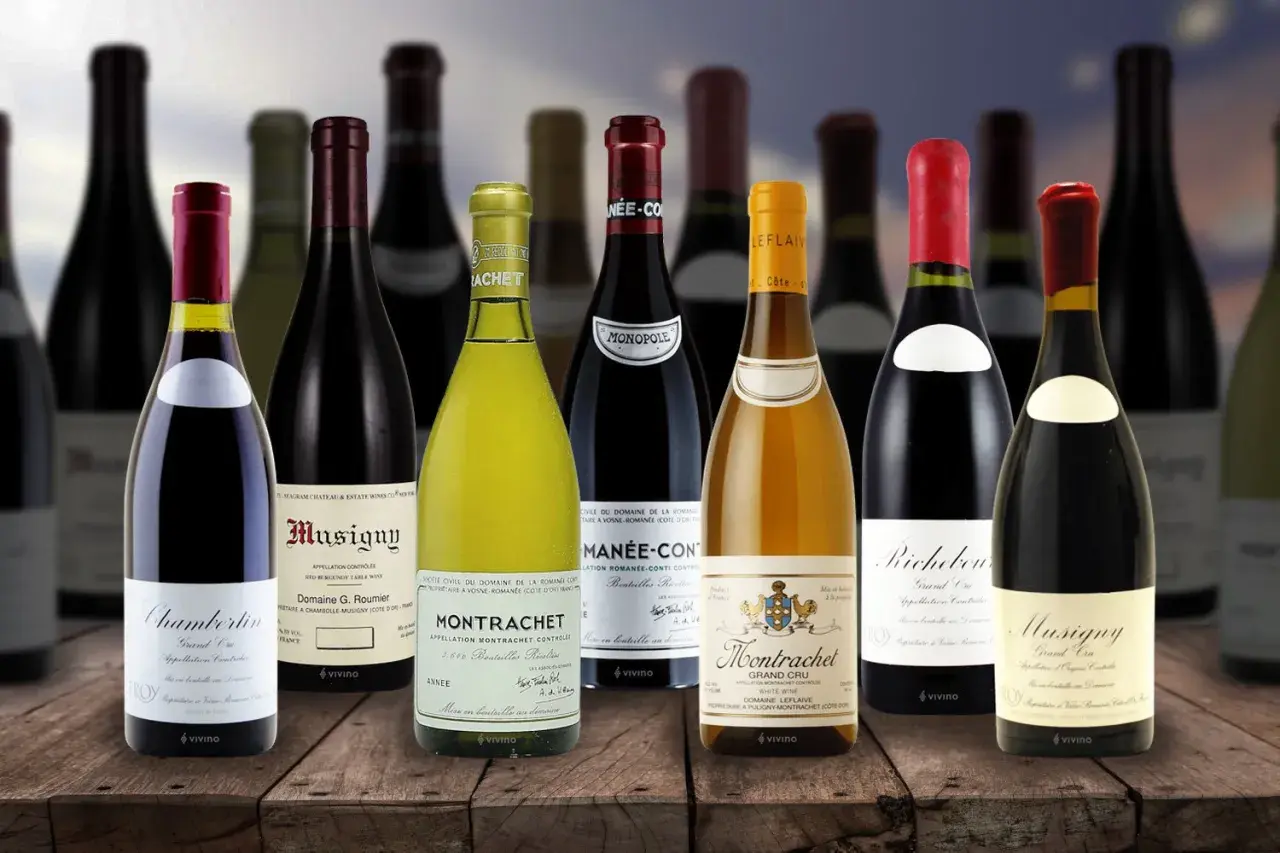 Una selezione di bottiglie costose di vino pregiato, tra cui Montrachet e Musigny, disposte su un tavolo di legno.