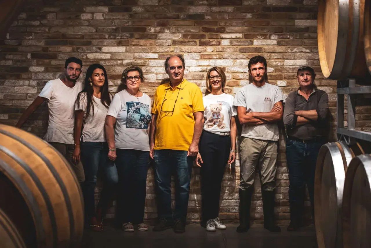 La famiglia al completo di Ca del Bric, in posa tra botti di legno e mattoni antichi, pronta a condividere la passione per il vino.