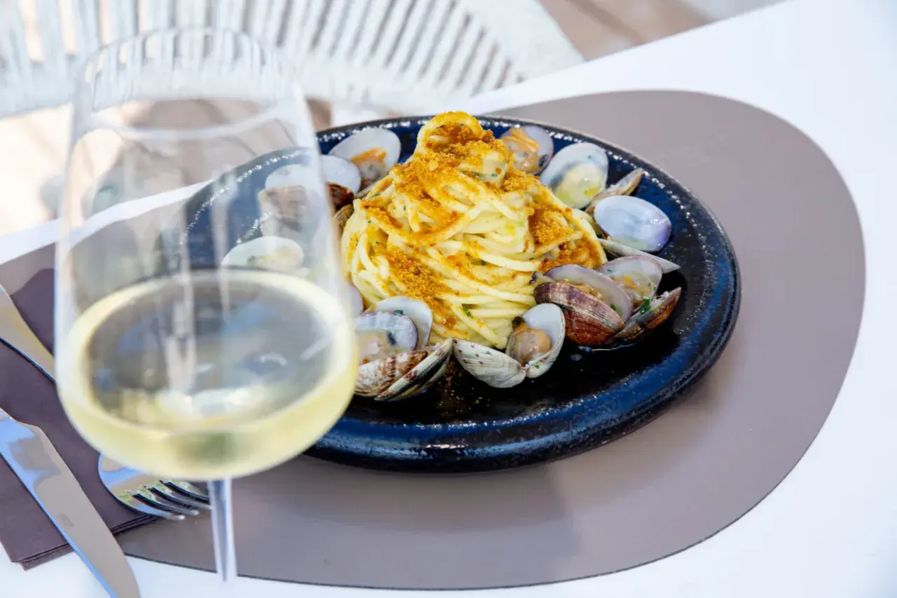 Un bicchiere di vino bianco, perfetto per gli abbinamenti con spaghetti alle vongole. Un piatto di mare invitante.
