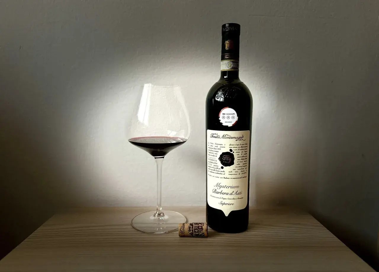 Un calice di Barbera d'Asti Mysterium e la sua bottiglia, un assaggio delle migliori cantine Asti.