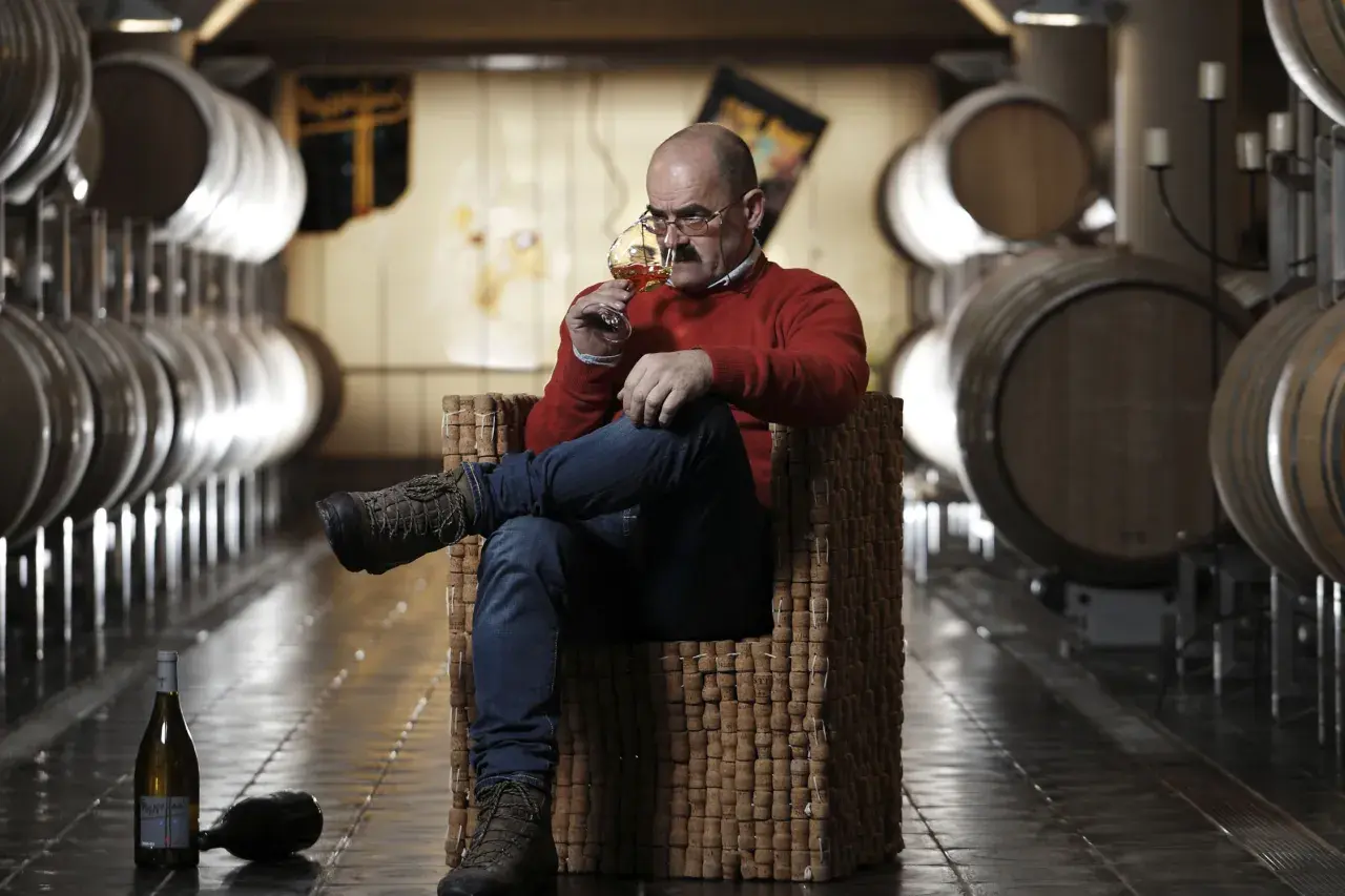 Uomo assapora vino Franz Haas in cantina tra botti.