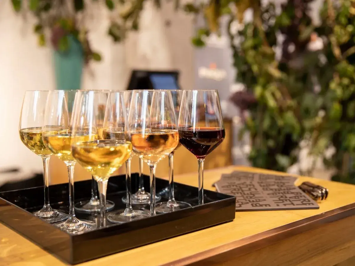 Calici di vino bianco, rosato e rosso su un vassoio nero. Un'esperienza di degustazione che non è barricata, ma aperta a tutti i sapori.