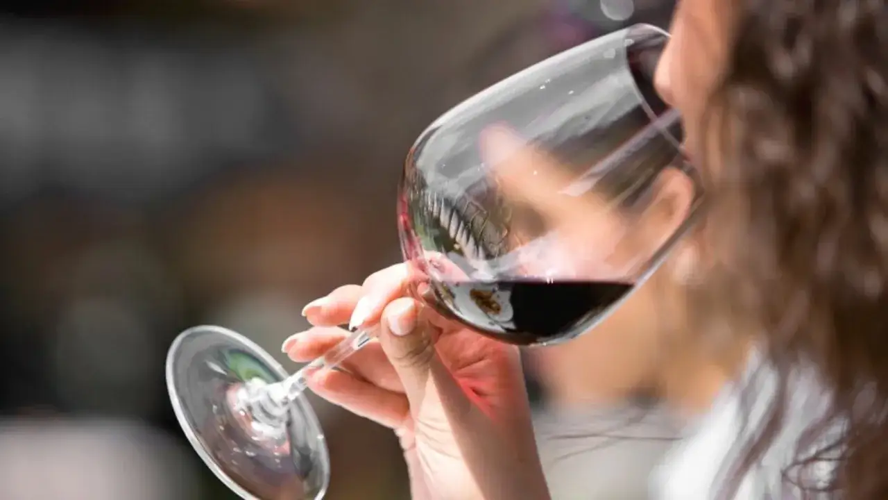Donna assapora un bicchiere di vino rosso, un momento di piacere che racchiude il suo abboccato significato.