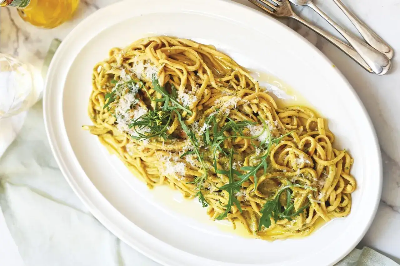 Pasta al pesto, guarnita con rucola e parmigiano. Un'idea perfetta su cosa abbinare alla pasta al pesto per un pasto fresco e saporito.