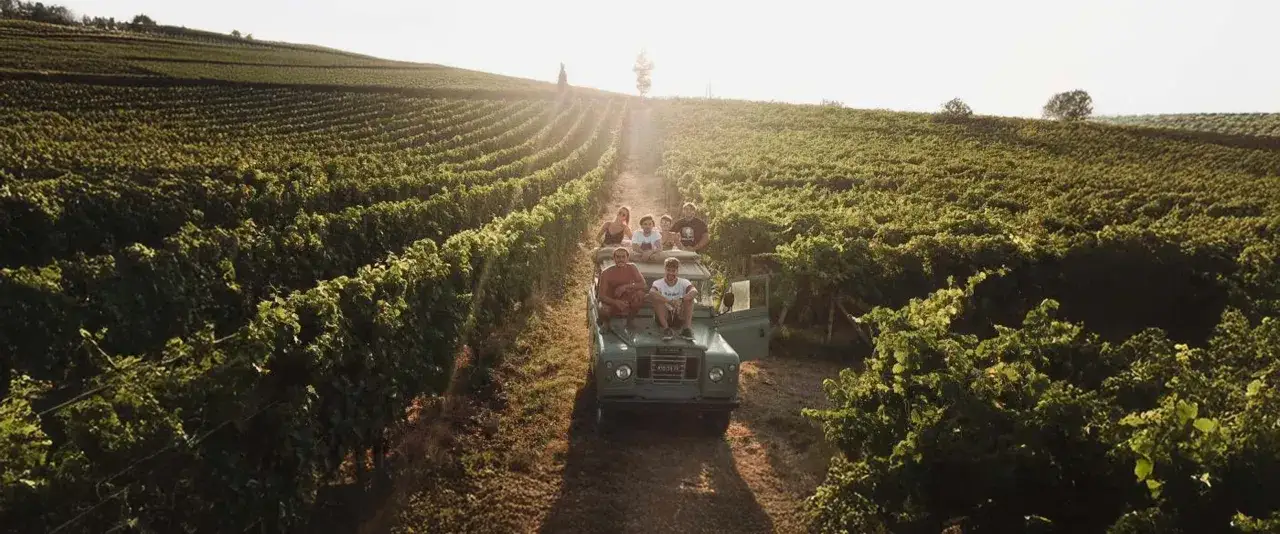 Un gruppo di amici in fuoristrada tra i vigneti del Piemonte, godendosi un'esperienza di degustazione vini.
