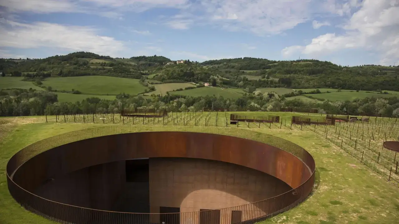 Un moderno complesso architettonico si fonde con il paesaggio collinare toscano, ospitando le cantine Chianti.