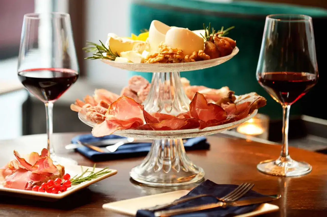 Un invitante aperitivo in cantina con taglieri di salumi e formaggi, noci, fichi secchi e bicchieri di vino rosso.