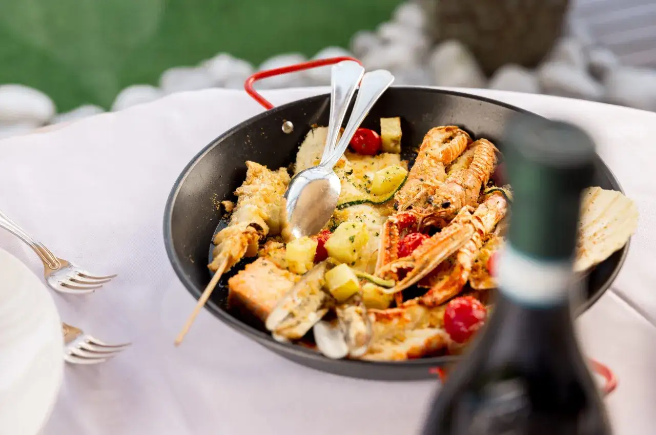 Piatto di pesce misto con scampi, patate e pomodorini, perfetto per i lugana abbinamenti.