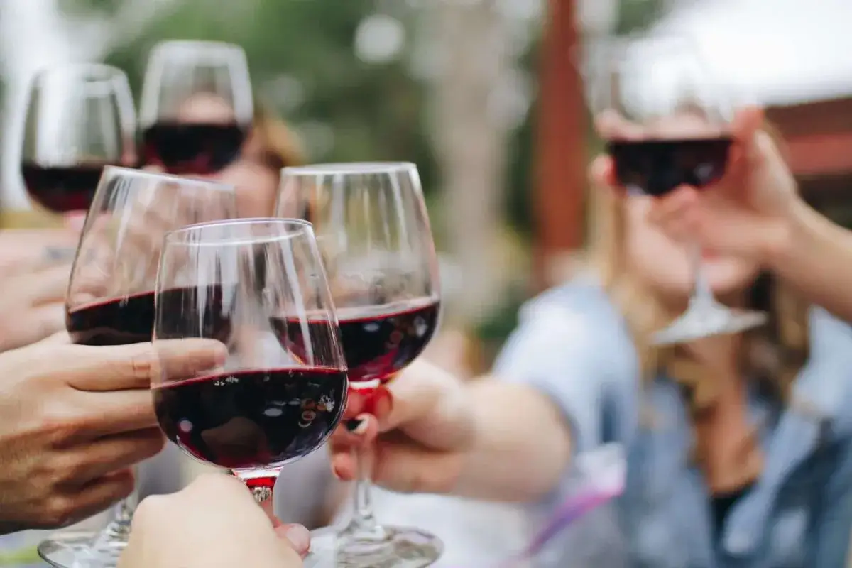 Calici di vino rosso sollevati in un brindisi, un momento di gioia condivisa dal significato etereo.