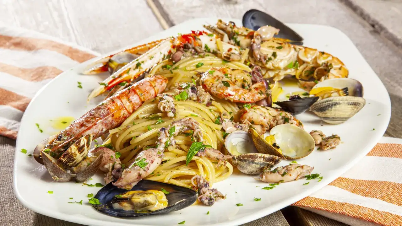 Spaghetti allo scoglio con scampi, gamberi, calamari e cozze. Un piatto di mare perfetto con un vino bianco fresco.