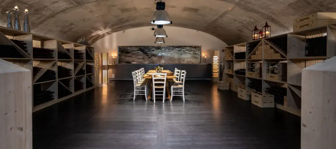 Cantina con tavola apparecchiata e scaffali pieni di bottiglie di franz haas wein.