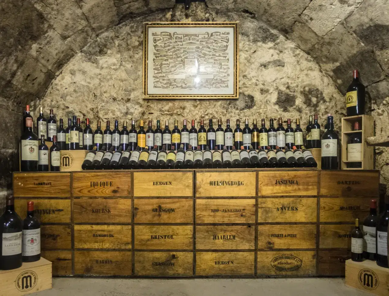 Cantina con bottiglie di vino e casse di legno. Alcune bottiglie sembrano vecchie, suggerendo che il vino scade.