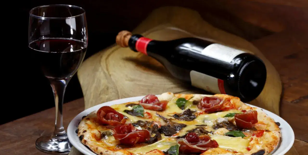 Pizza con salame piccante e vino rosso: un abbinamento perfetto per una serata gustosa.