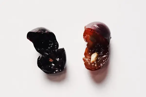 Due acini d'uva tagliati a metà, uno scuro e uno più chiaro, evocano la macerazione carbonica del vino.